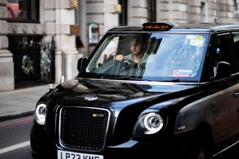 A black taxi driving through the bustling streets of London, capturing iconic urban life.